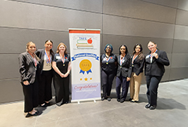  A group of teenage girls in professional dress stand by a banner